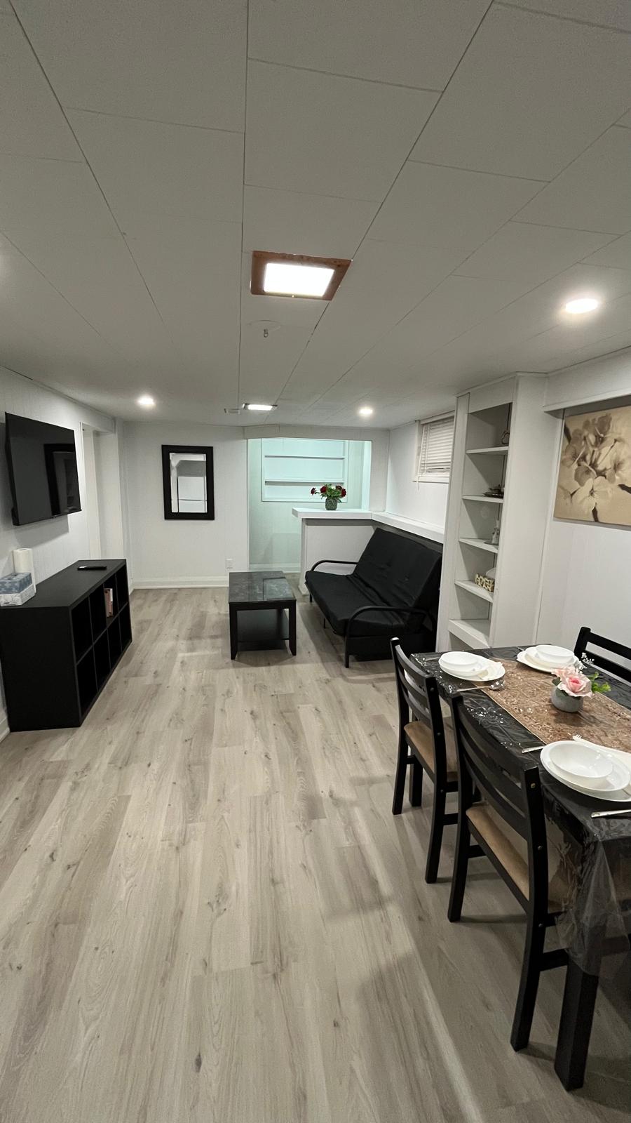 Finished basement living and dining area staged with light grey luxury vinyl plank